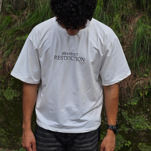 Person wearing a white t-shirt with text standing in a forest