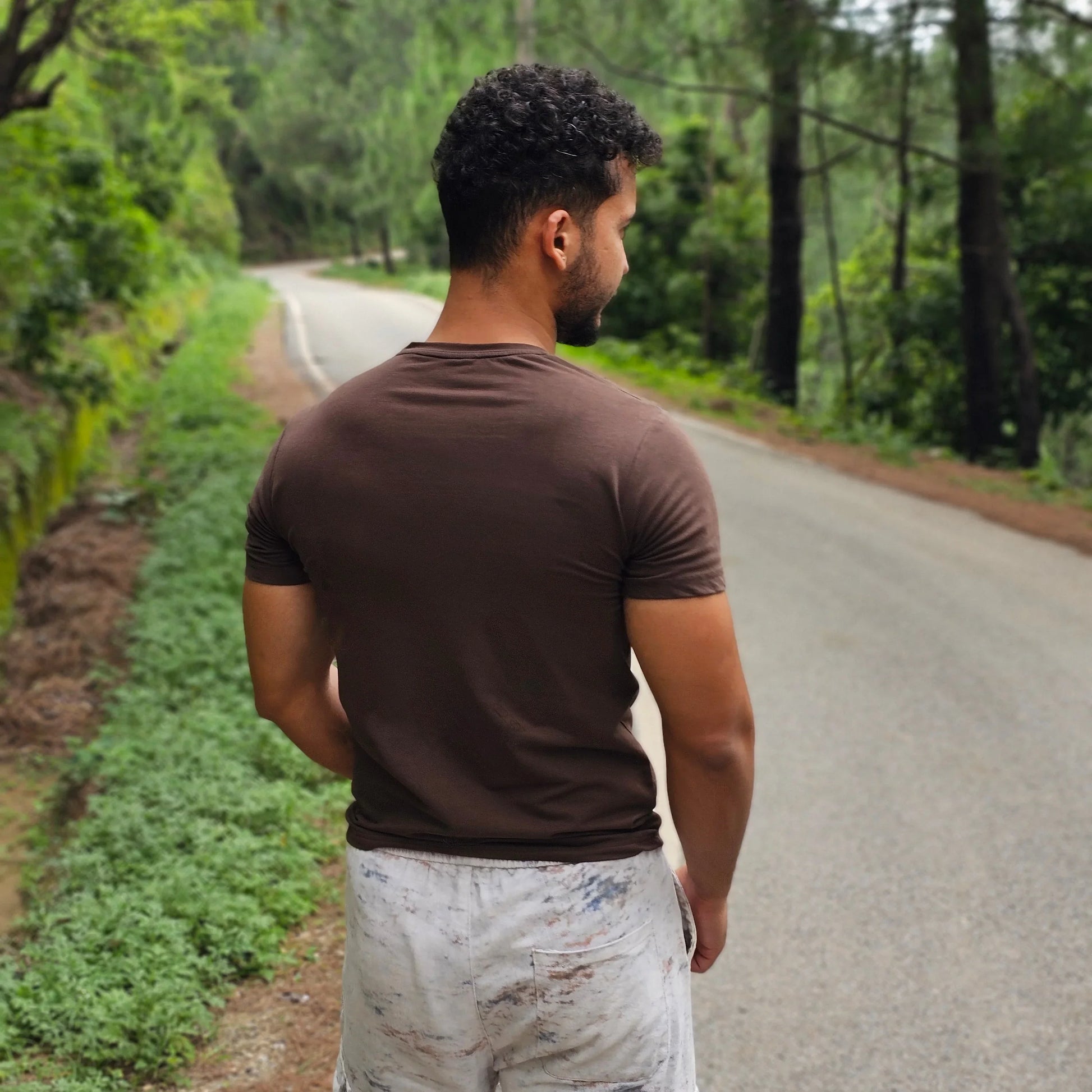 Person standing outdoors with trees and a road in the background