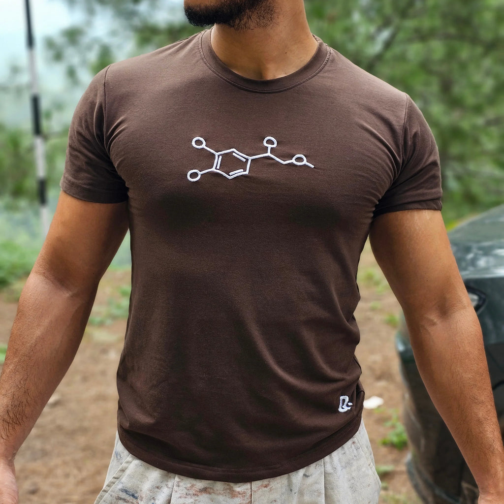 Man wearing a brown t-shirt with a white embrioder design outdoors