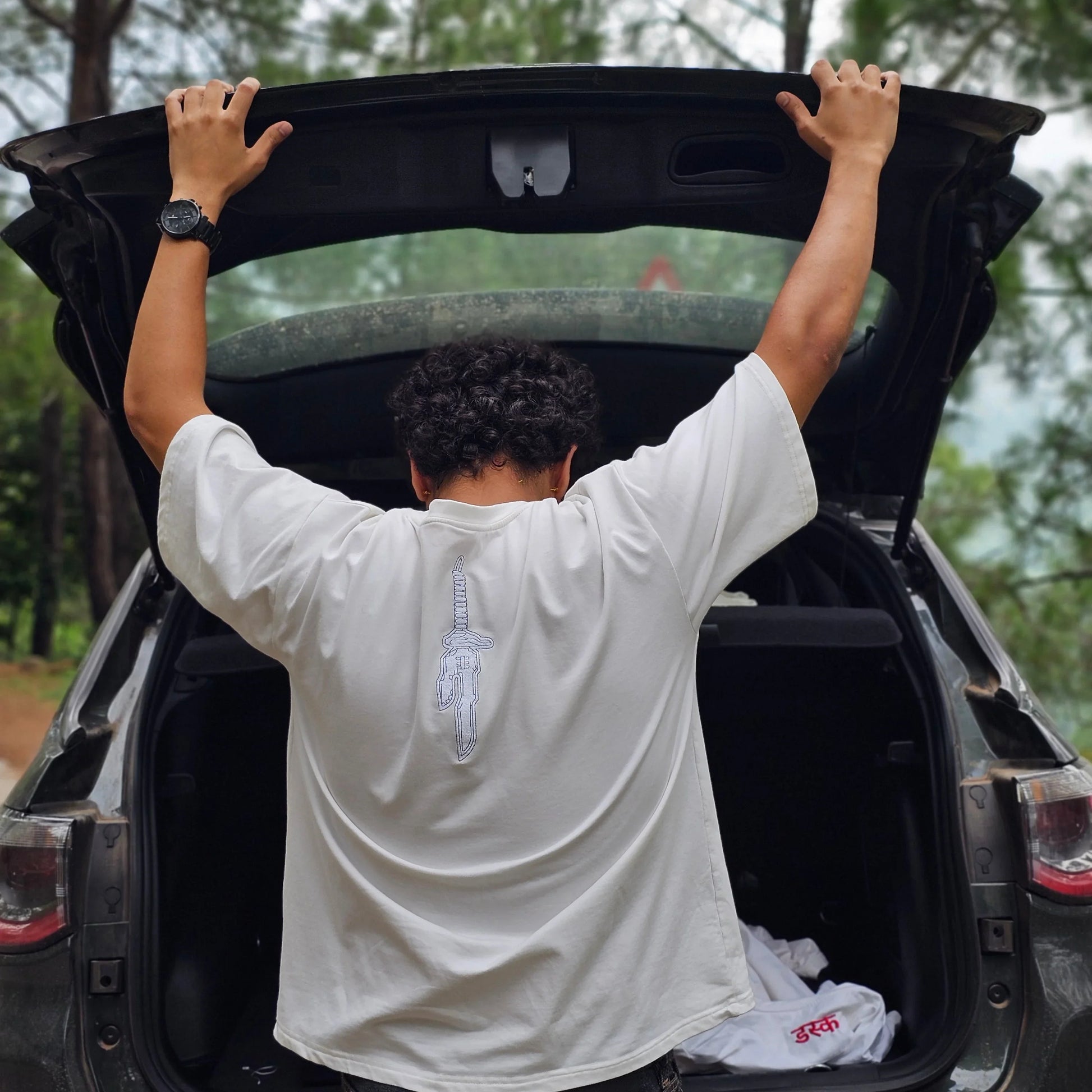 Person opening the trunk of a car with trees in the background