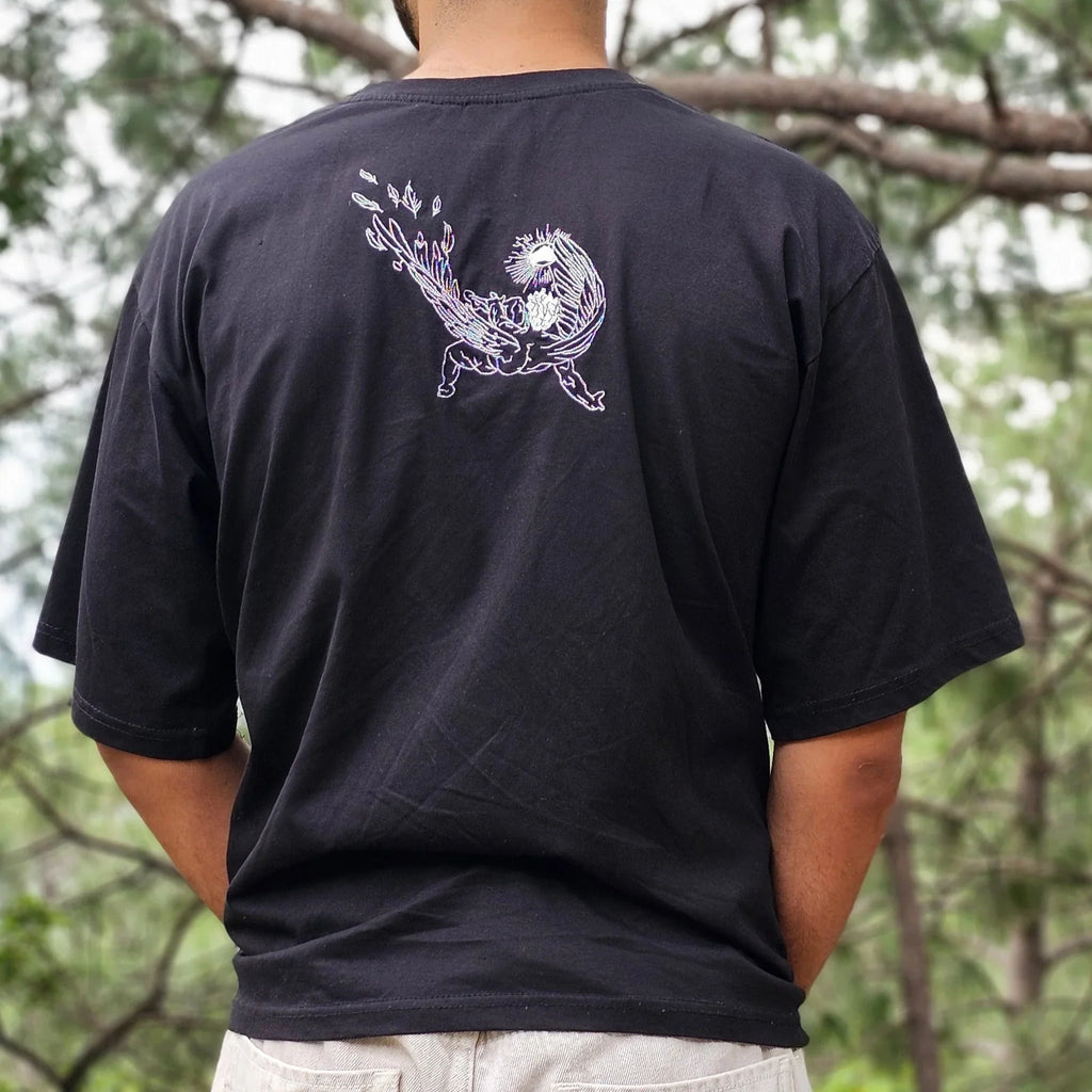 Person wearing a black shirt with a white design outdoors among trees