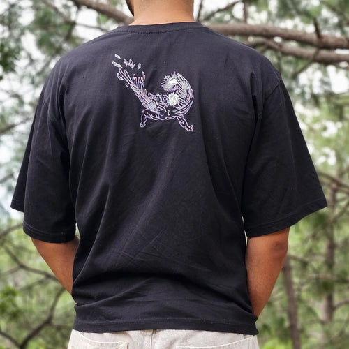 Person wearing a black shirt with a white design outdoors among trees