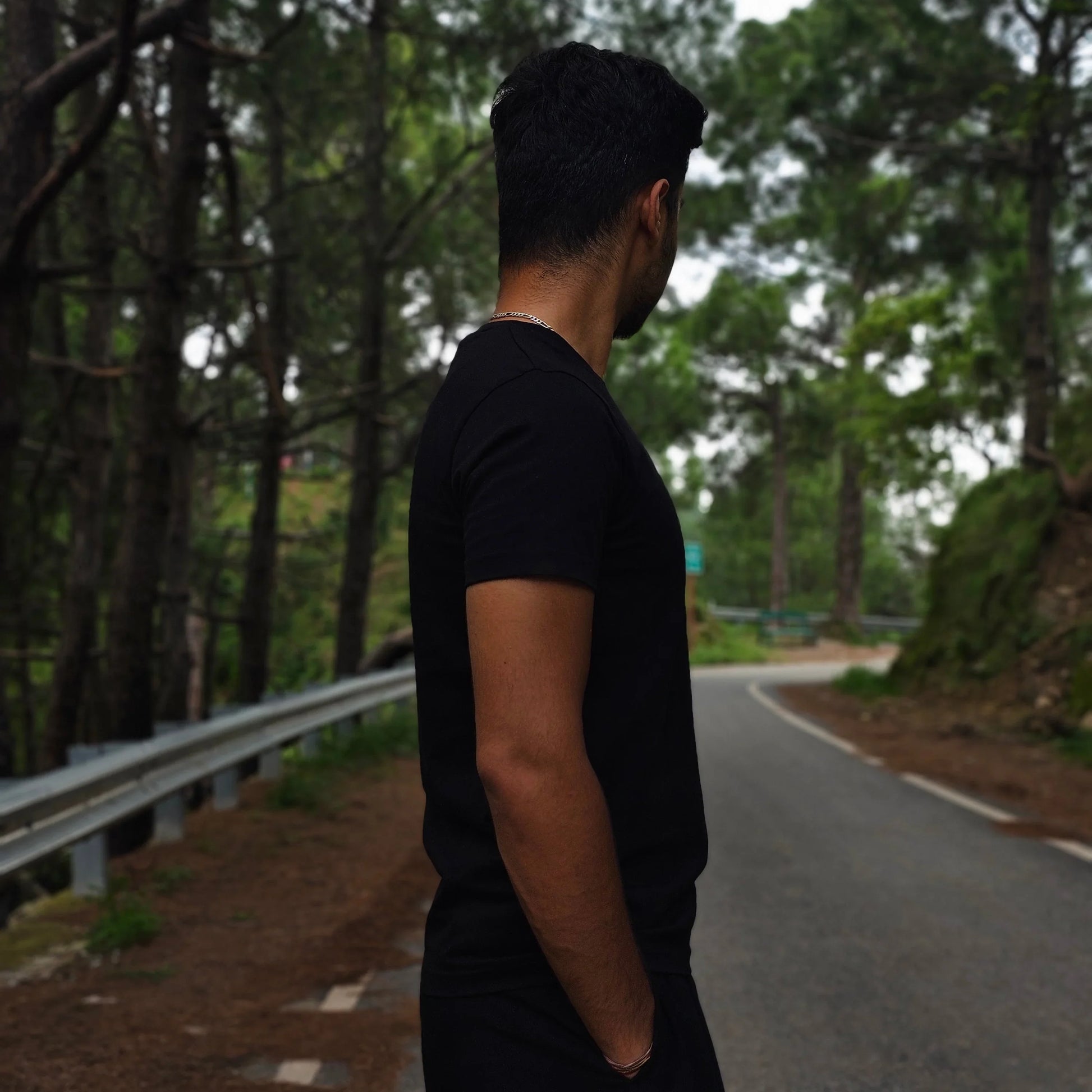 Person standing on a road with trees in the background