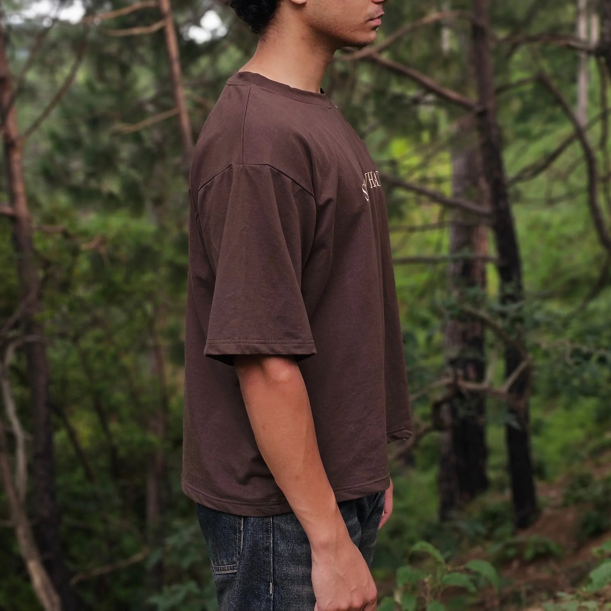 Person standing in a forest with trees and greenery in the background