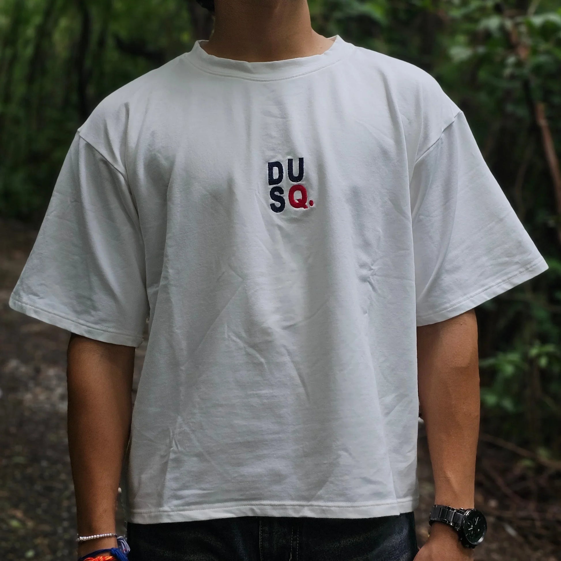 Person wearing a white t-shirt with logos outdoors