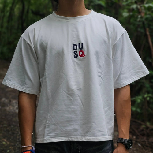 Person wearing a white t-shirt with logos outdoors
