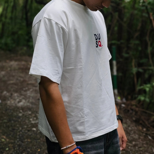 Person wearing a white t-shirt with logos outdoors