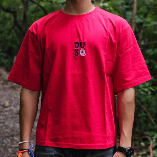Person wearing a red shirt with a logo in a forest setting
