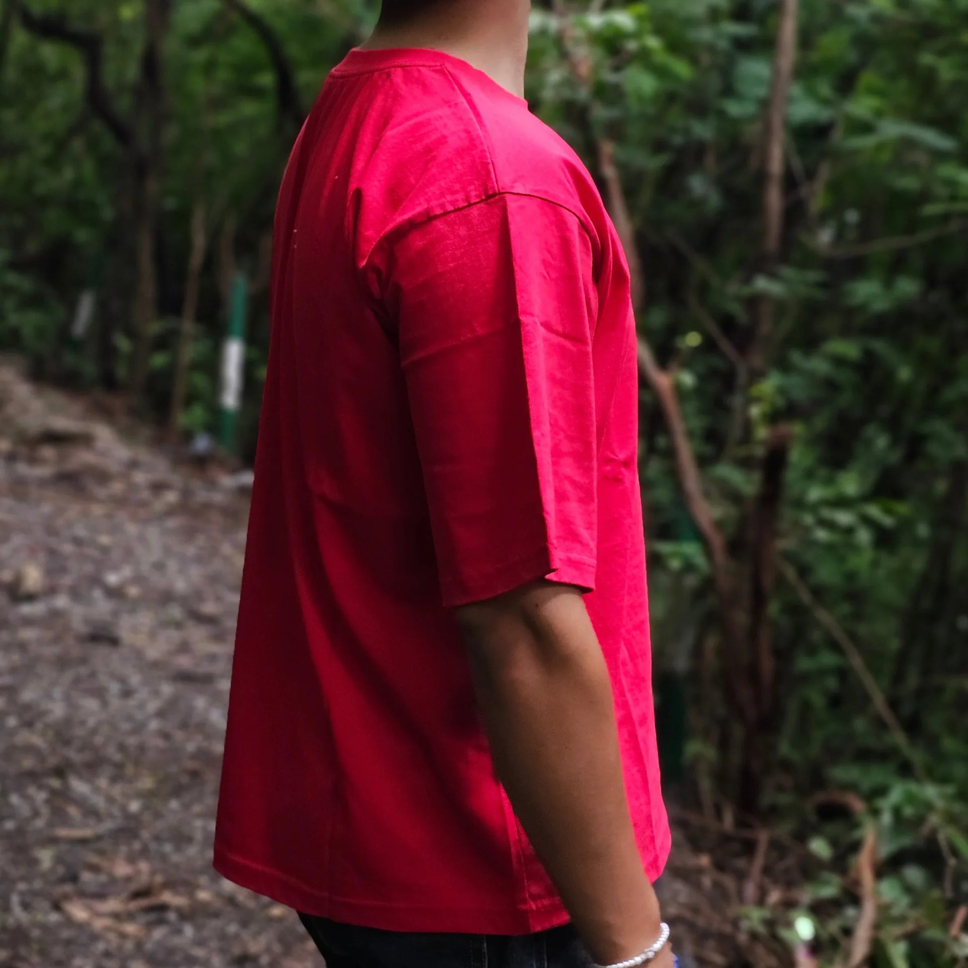 Person wearing a red shirt standing in a forest