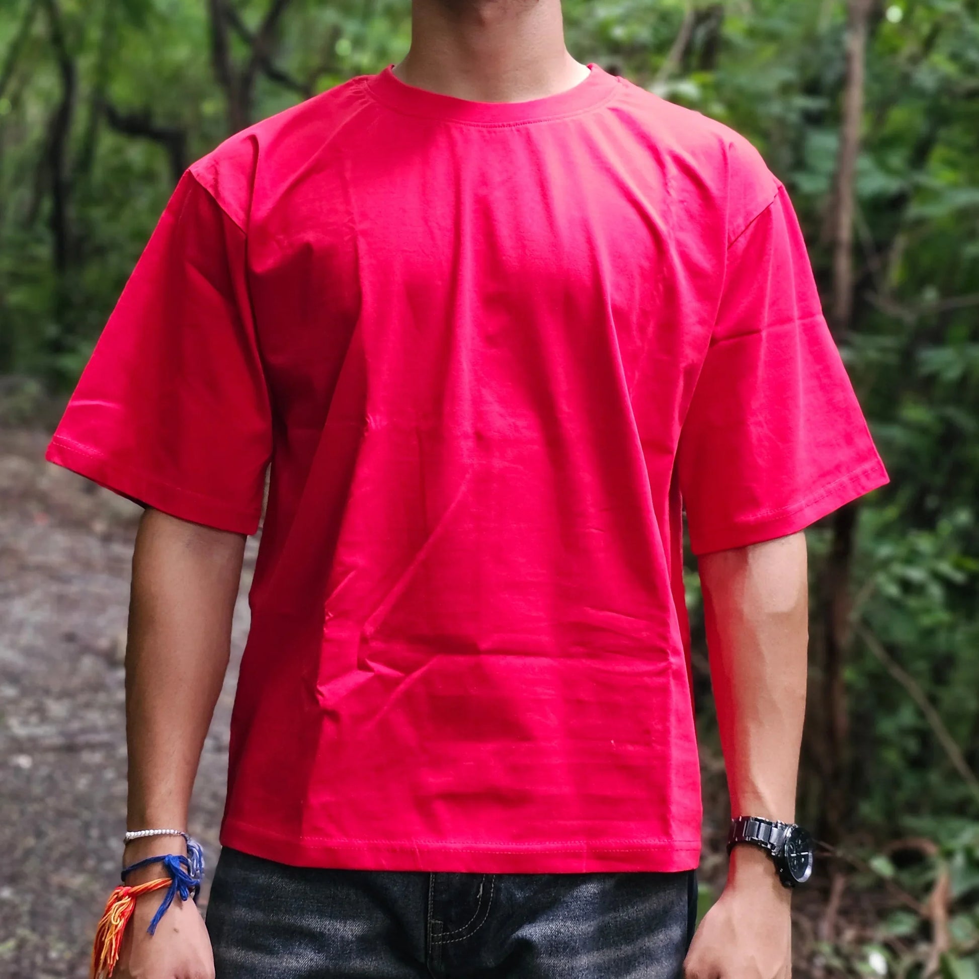 Person wearing a red shirt standing outdoors with trees in the background
