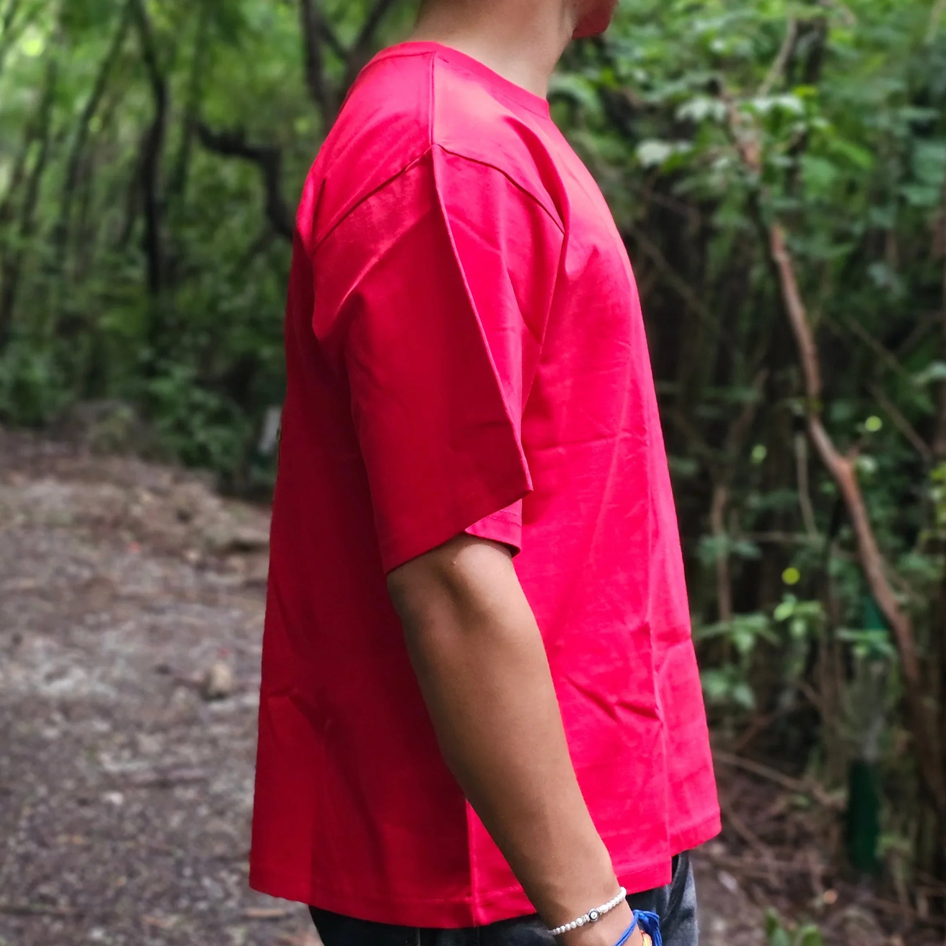 Person wearing a red shirt standing in a forest