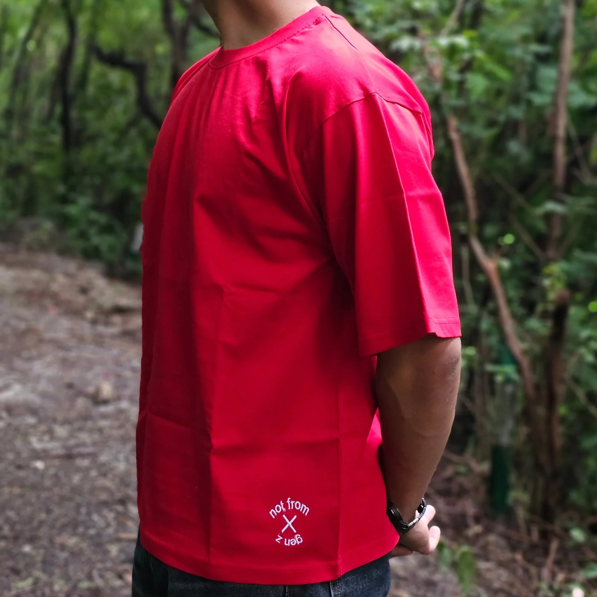 Person wearing a red shirt with a logo in a forest setting