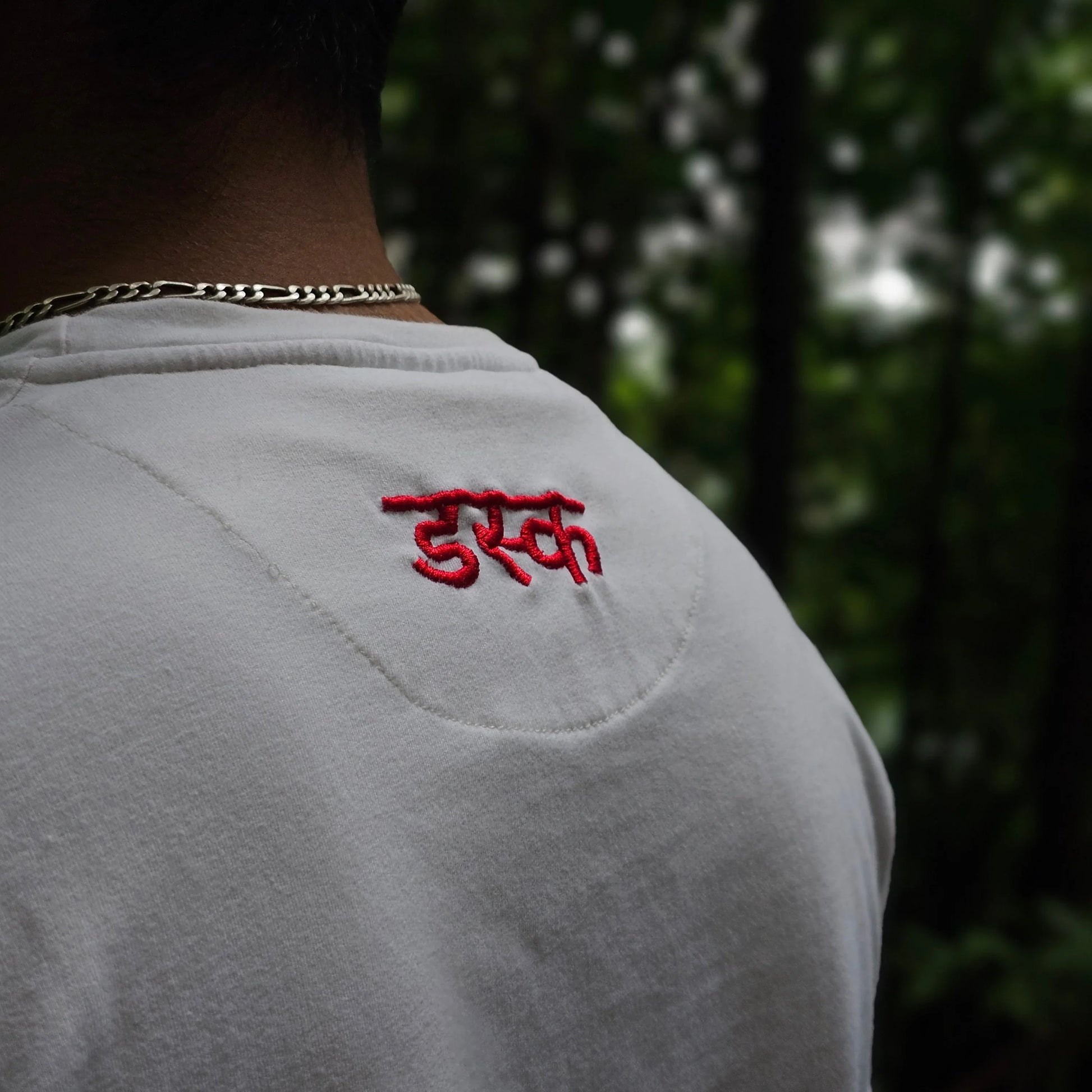White shirt with red embroidery on a blurred natural background
