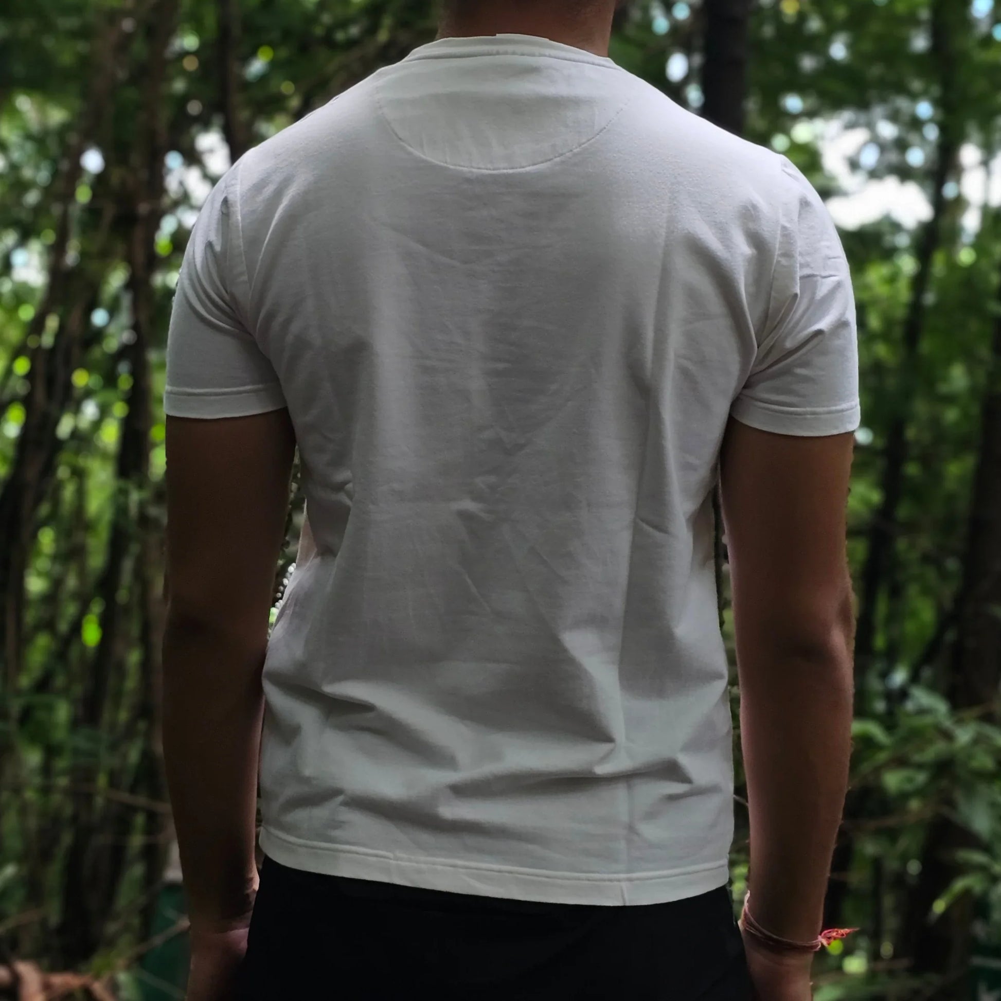 Person in a white shirt standing in a forest