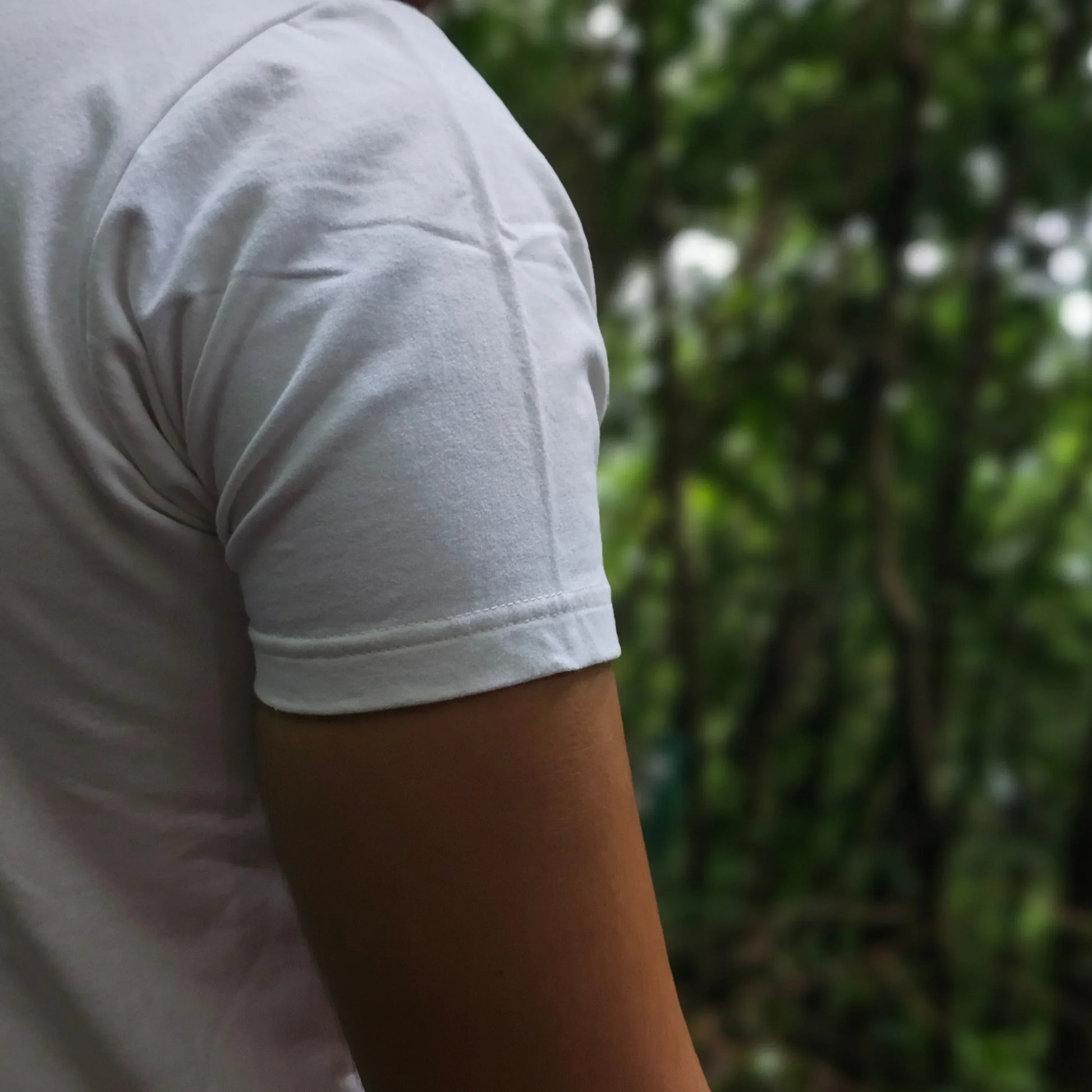 Person wearing a white t-shirt with a blurred green background
