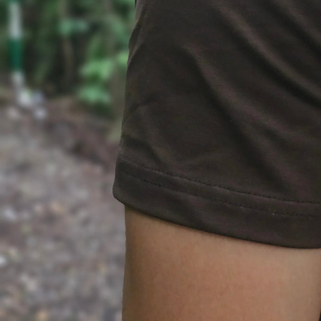 Close-up of a person wearing a dark brown shirt with a blurred natural background